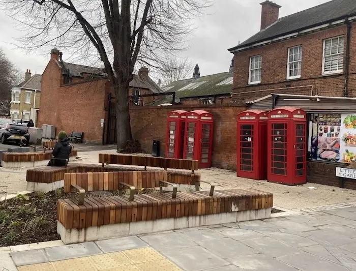 New benches and rain gardens next to four old red telephone boxes in Saddler Square Enfield Town